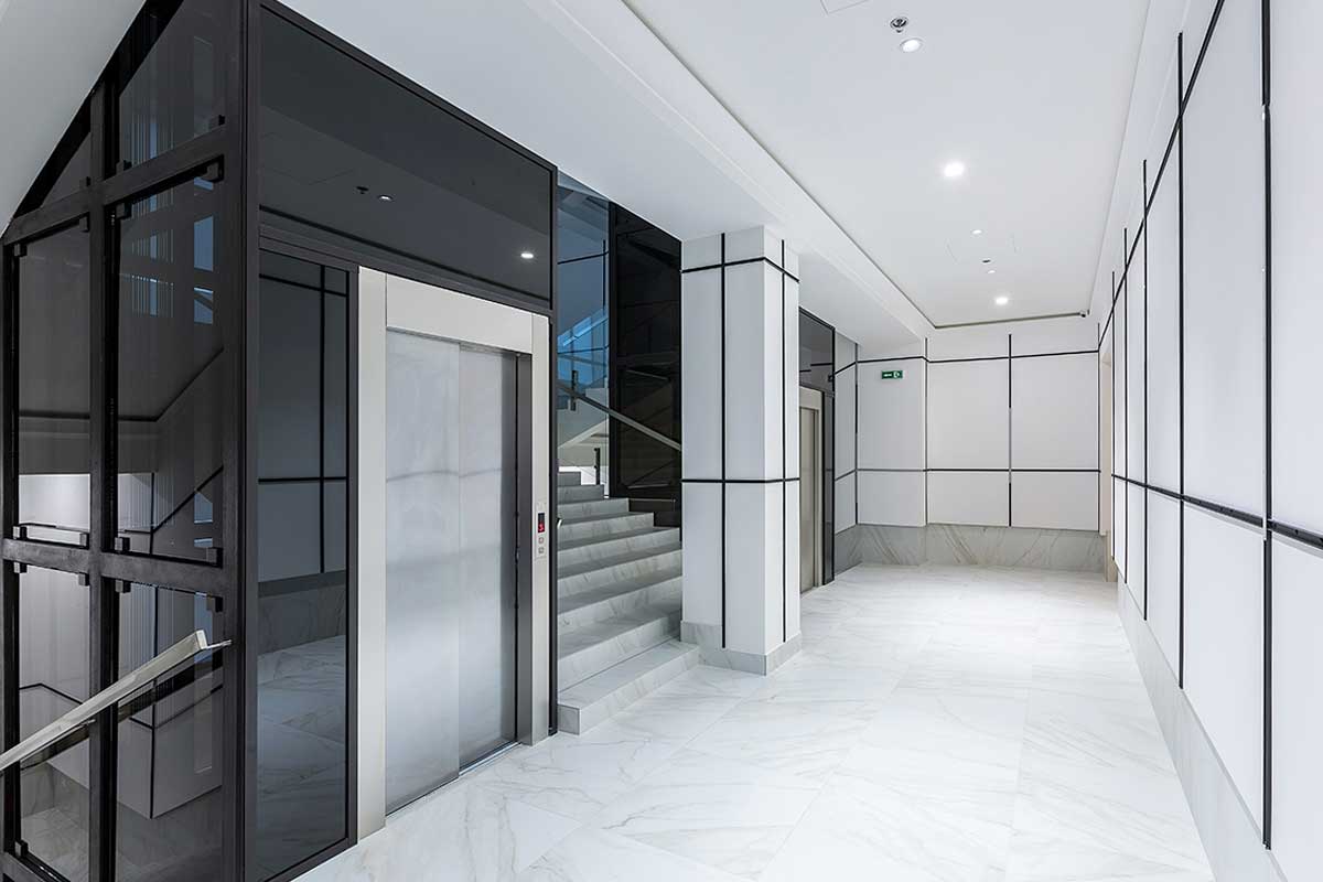 Modernes Treppenhaus im Bürogebäude mit zwei Aufzügen.